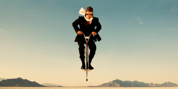 businessman-on-pogo-stick-in-desert-picture-id108347844